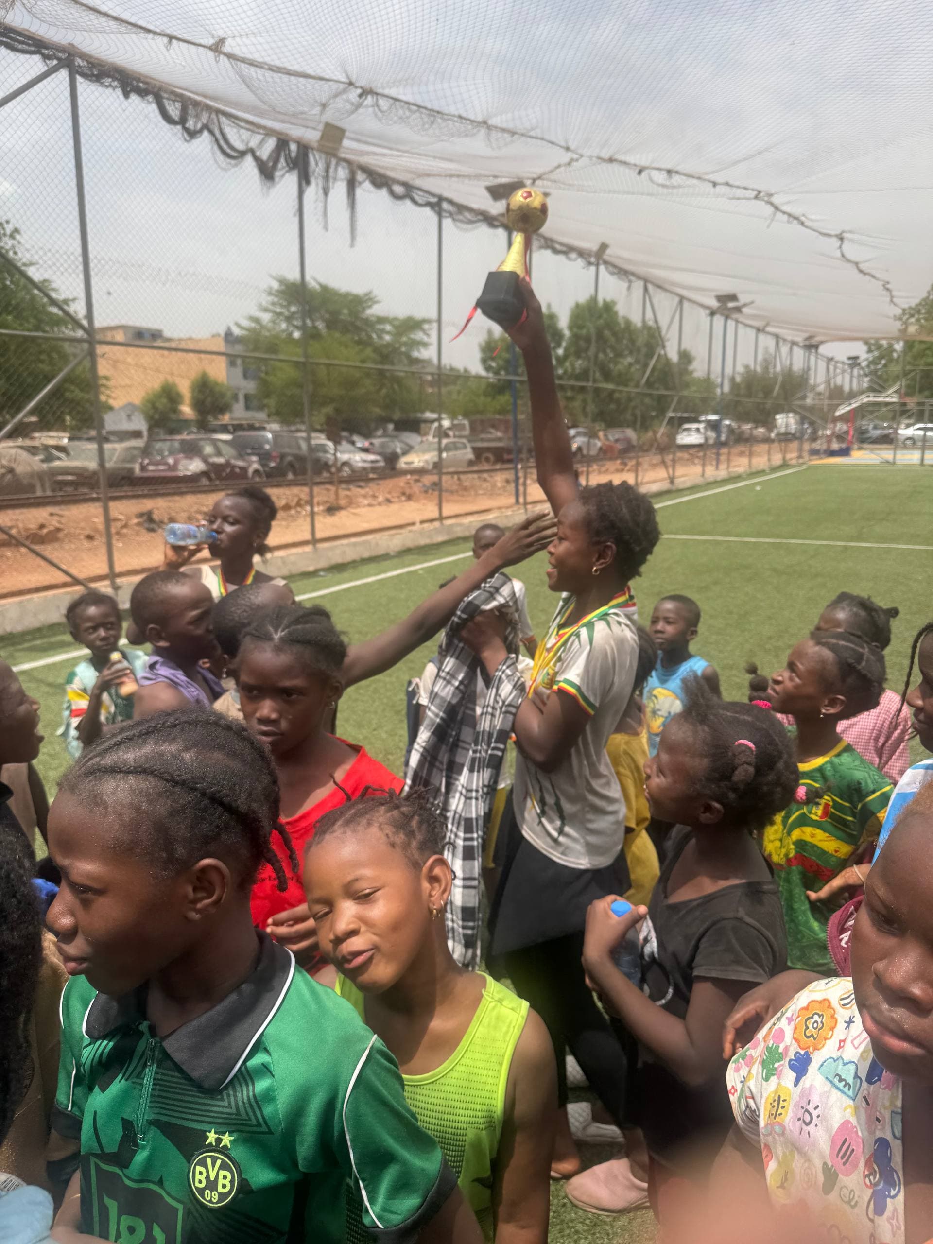 Groupe réuni autour d’un trophée sur un terrain